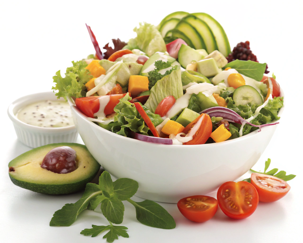 A vibrant and naturally delicious bowl of mixed green salad with colorful vegetables and a creamy dressing.