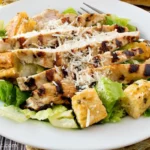 A vibrant Grilled Chicken Caesar Salad with fresh romaine, juicy chicken, and creamy dressing.